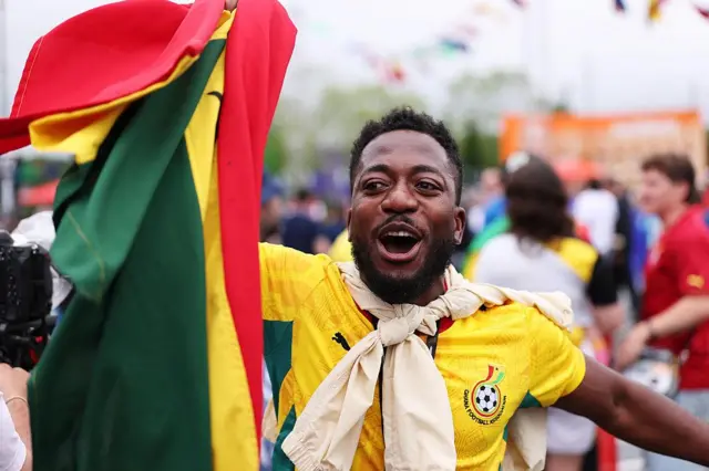 Un supporter ghanéen, vêtu des couleurs de son équipe, danse devant le stade