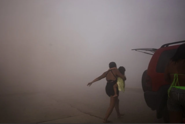 Una mujer corre con un niño para ponerse a salvo durante un terremoto, en La Guaira, Venezuela, 24 de junio de 2026. REUTERS/Maxwell Briceno