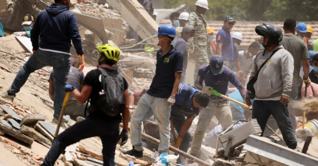 Grupos de personas buscan supervivientes entre los escombros de un edificio destruido en Caracas.