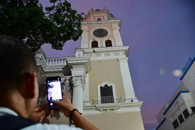 Un hombre hace una foto de la torre de una iglesia con su teléfono móvil.