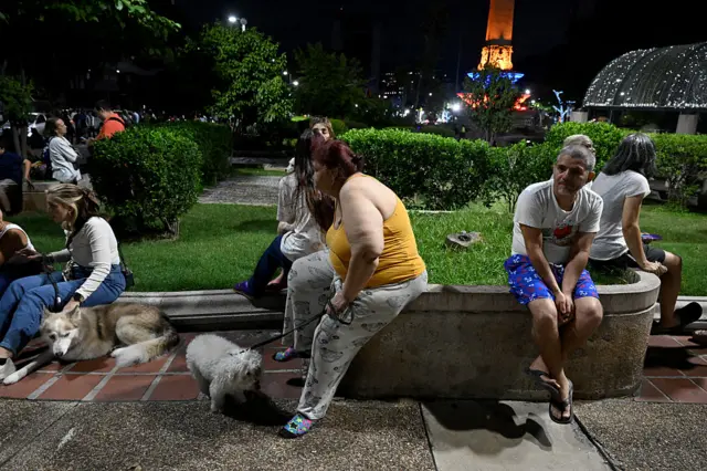 Gente sentada en una plaza de noche en Caracas.