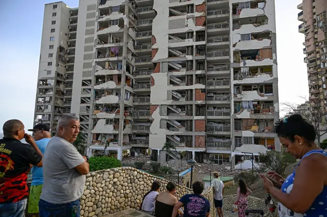 personas observan un edificio destruido en La Guaira
