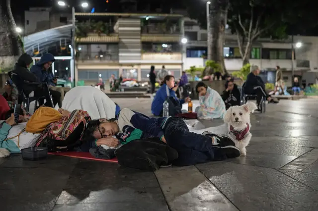 Una mujer duerme con su perro en la calle en Caracas.