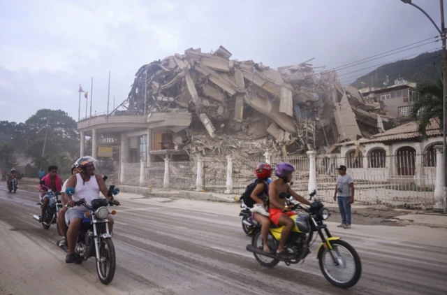 Varias personas en motocicletas pasan frente a un edificio derrumbado después de un terremoto, en La Guaira, Venezuela, el 24 de junio de 2026. REUTERS/Maxwell Briceno