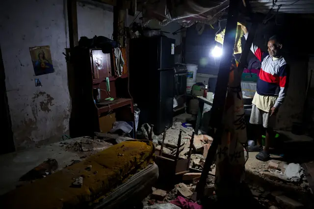 Un hombre ilumina con un farol una habitación afectada por el terremoto en Venezuela.