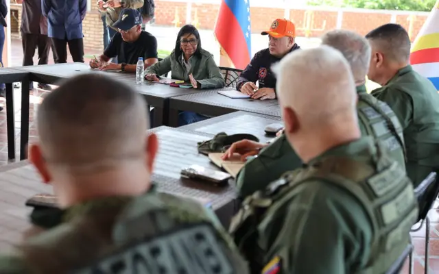 Jorge Rodríguez, Delcy Rodríguez y Diosdado Cabello sentados a una mesa junto a militares uniformados