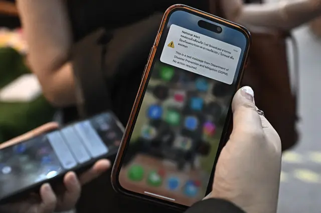 Una persona muestra una alerta de sismo en su teléfono