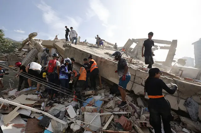 Personas realizando labores de rescate bajo una pila de escombros