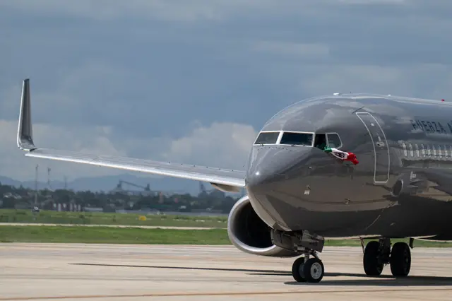 Un avión con una bandera mexicana en la ventanilla de la cabina de pilotos