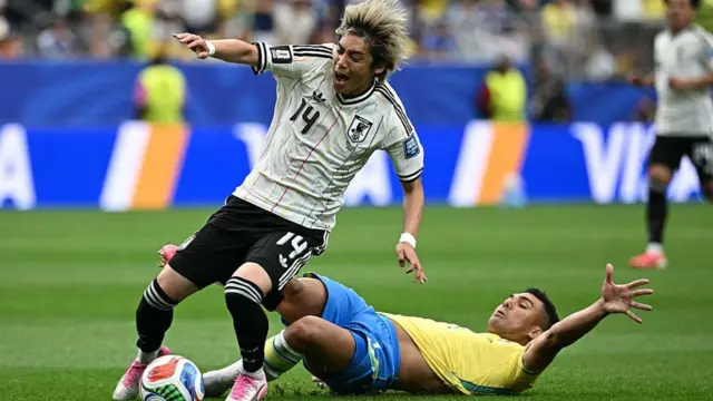 Brazil's midfielder #05 Casemiro (R) tackles and fouls Japan's midfielder #14 Junya Ito (L) leading to a yellow card during the 2026 World Cup round of 32 football match between Brazil and Japan.
