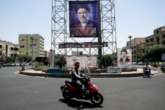Abagendesha amapikipiki bariko bararengana baca iruhande y’icapa kiriko ifoto y’umuyobozi wa Iran, Mojtaba Khamenei, i Teherani, ku wa 28 Ruheshi (6) 2026 (ifoto mbarankuru)