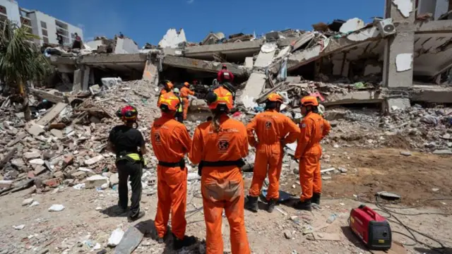 Rescatistas observan un edificio derrumbado