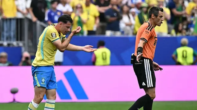 Brazil's forward #22 Gabriel Martinelli (L) reacts next to Italian referee Maurizio Mariani during the 2026 World Cup round of 32 football match between Brazil and Japan.