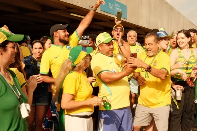 Torcedores com uniformes do Brasil e réplica da Copa do Mundo