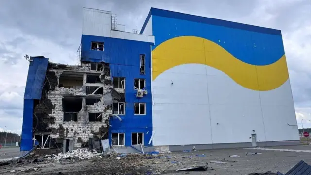 Здание, выкрашенное в синий и желтый цвета, с поврежденным фасадом