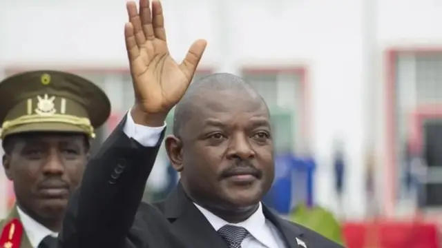 Perezida Pierre Nkurunziza yambaye kositime yirabura, ishati igomba kwera n'ikaruvati, yadugije ukuboko kw'i buryo, aramutsa. Ariko araba ahantu hatazwi