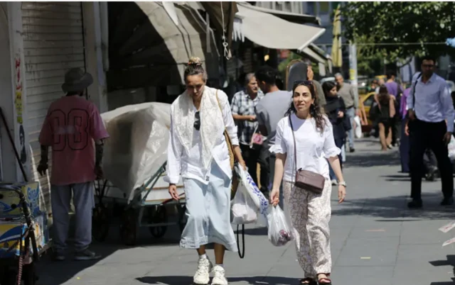 امرأتان تسيران في الشارع وهما تحملان مشترياتهما