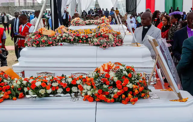 Abasaseredoti n'abandi bakozi b'amadini bahagaze iruhande y'amasandugu arimwo ibiziga vy'abanyeshure bishwe n'umuriro wadutse mw'ijoro mu buraro kw'ishure rya Utumishi Girls