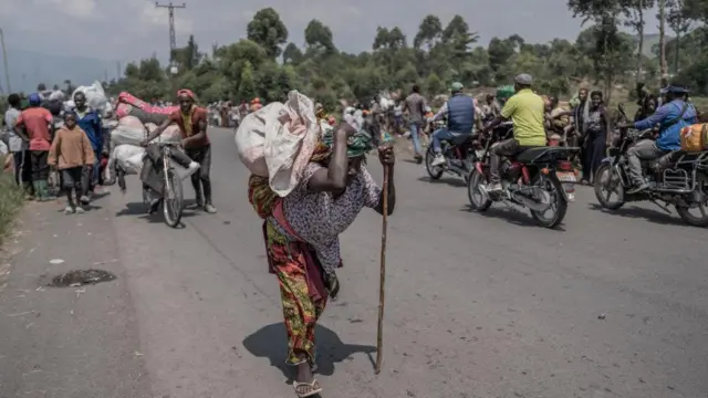 Umugore wikoreye bimwe mu byo atunze, mu gihe abantu bari barimo guhunga bava muri teritwari ya Masisi, mu ntara ya Kivu ya Ruguru, nyuma y'imirwano ikaze hagati y'inyeshyamba za M23 n'ingabo za Repubulika ya Demokarasi ya Congo, aha ni mu muhanda uri hafi y'i Sake, ku itariki ya 7 Gashyantare (2) mu mwaka wa 2024.