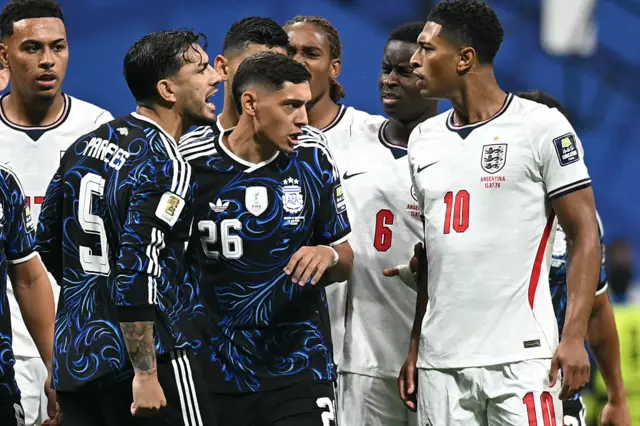 (Da esquerda) O meio-campista argentino nº 05 Leandro Paredes, o zagueiro argentino nº 26 Nahuel Molina, o zagueiro inglês nº 06 Marc Guehi e o meio-campista inglês nº 10 Jude Bellingham discutem durante a partida semifinal do torneio de futebol da Copa do Mundo de 2026 entre Inglaterra e Argentina no Atlanta Stadium, em Atlanta, em 15 de julho de 2026. (Foto de Paul ELLIS / AFP via Getty Images)