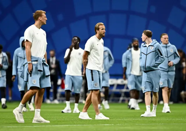 Kane e seus companheiros de time examinam o campo