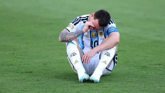 Lionel Messi, sentado en el campo de juego y refregándose el ojo derecho