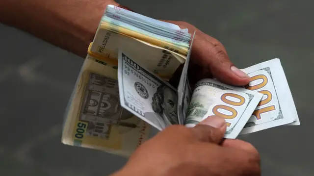دستان یک مرد در حال شمردن اسکناس صد دلاری
