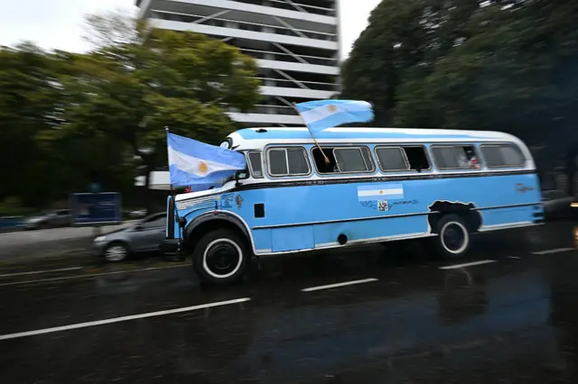 Arjantin’in başkenti Buenos Aires’te Arjantin bayraklarıyla süslenmiş ve taraftarları taşıyan bir otobüs caddede ilerliyor