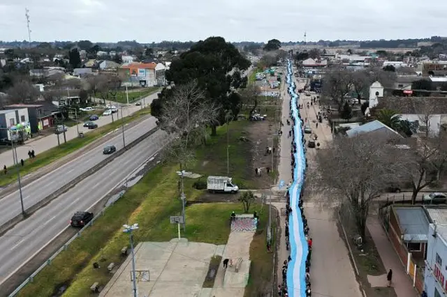 Cette vue aérienne montre des personnes déployant un drapeau national argentin géant dans les rues de Batan