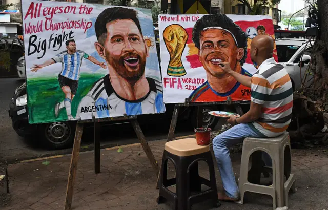 Gurukul Sanat Okulu’ndan bir öğretmen, FIFA Dünya Kupası finali öncesinde okulun dışında Arjantinli futbolcu Lionel Messi (solda) ve İspanyol futbolcu Lamine Yamal’ın (sağda) yer aldığı bir poster hazırlıyor.