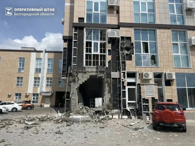 Многоэтажный дом с дырой от взрыва на первом этаже.
