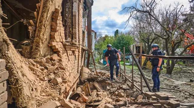 Украинские спасатели у стены разрушенного дома