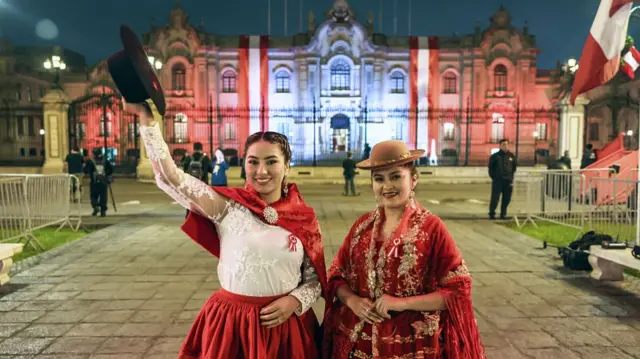 Mujeres en atuendos tradicionales frente al Palacio de Gobierno en el centro de Lima.