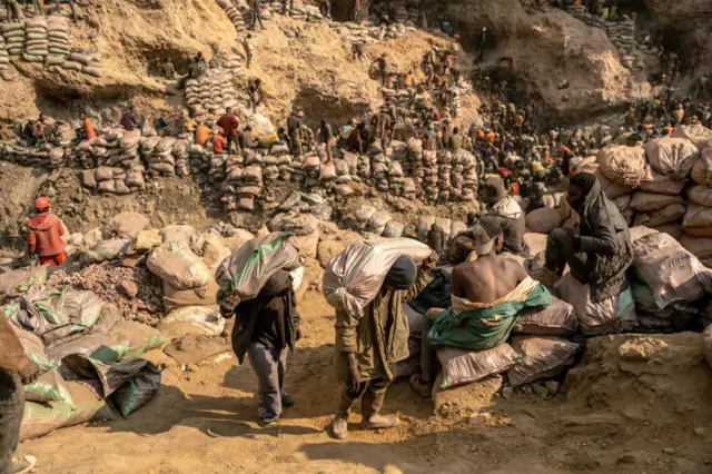 Abacukuzi bikoreye imifuka ku kirombe gicukurwamo umuringa (cuivre) na cobalt mu buryo bwa gakondo, hafi y’umujyi wa Kolwezi, mu ntara ya Lualaba, muri Repubulika ya Demokarasi ya Congo, ku itariki ya 20 Kamena (6) mu 2023.