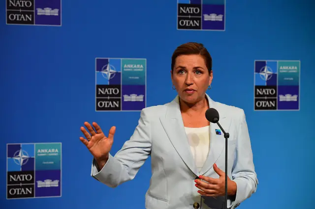 Frederiksen mikrofon önünde konuşuyor. Bir eli havada, üzerinde açık renk bir takım var.