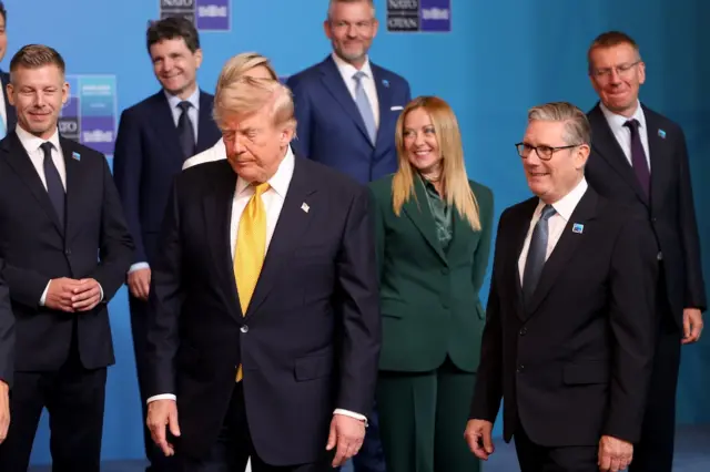 Trump ortada fotoğraf çekimi için yer alıyor Starmer sağda ona bakıyor geride diğer liderler.