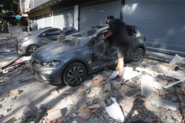 Un hombre intenta quitar escombros de encima de su automóvil