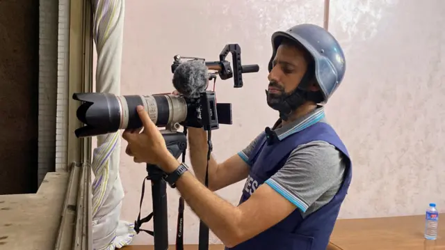 Umumenyeshamakuru wa Reuters akaba n’Umunya Palestina, Mohammed Salem, igihe yariko akurikirana amakuru ajanye n’ibitero vy’indege vya Israel muri Gaza. Ni ifoto mbarankuru ya Reuters yo ku wa 12 Gitugutu 2023.