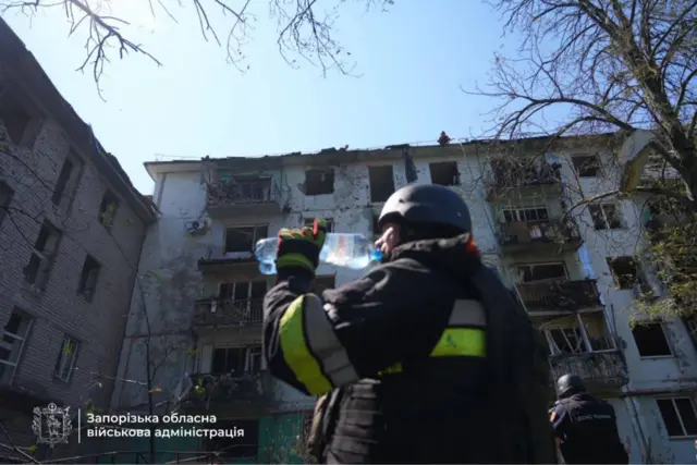 спасатель пьет воду на месте тушения пожара в доме в Запорожье