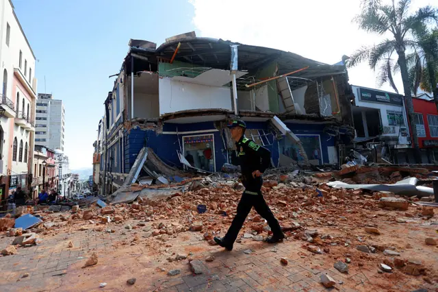 Un agente de policía camina entre los escombros de un establecimiento comercial dañado tras el terremoto en Manizales.