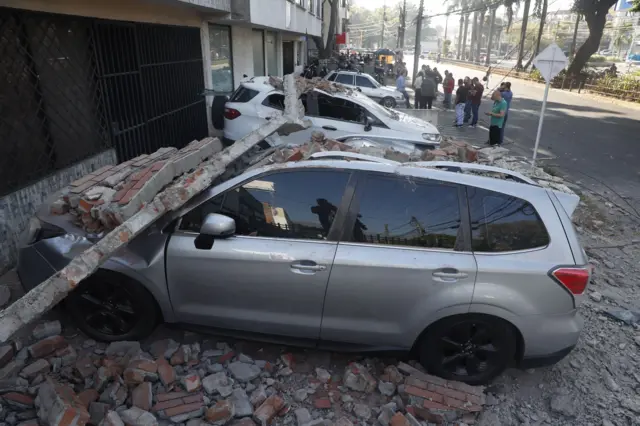 Una fila de carros estacionados destrozados por los escombros del terremoto
