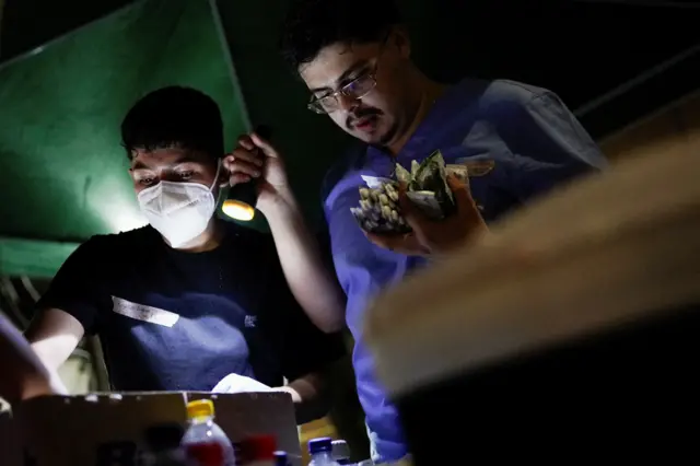 Alumbrados con linternas, personal médico revisa los medicamentos en el lugar de un edificio colapsado tras un terremoto, en Cali.