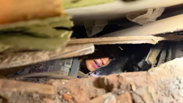Una mujer atrapada entre los escombros de un edificio.