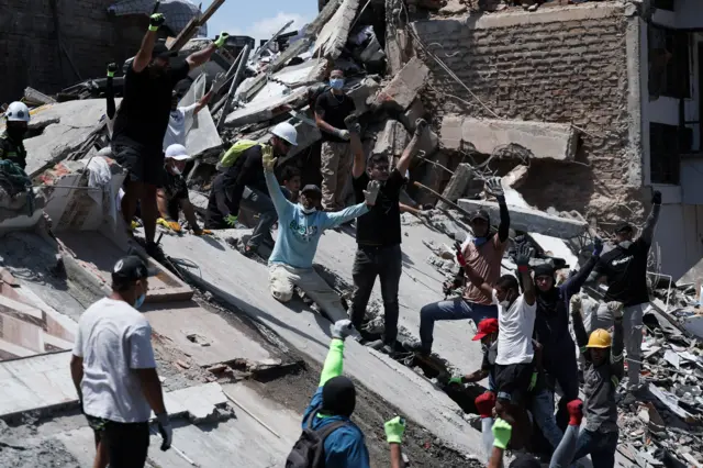 Personas hacen gestos mientras buscan sobrevivientes en el lugar de un edificio derrumbado tras un terremoto, en Pereira, Colombia, el 11 de agosto de 2026.