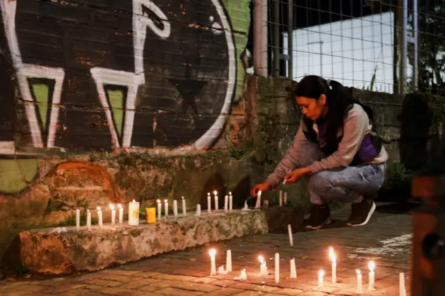 Una mujer enciende una vela en una vigilia en Manizales, Colombia