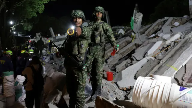 Un soldado sostiene una linterna mientras continúan las labores de rescate en el lugar de un edificio dañado tras un terremoto.