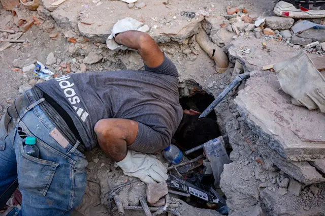 Un voluntario busca sobrevivientes entre los escombros de un edificio derrumbado en Pereira.