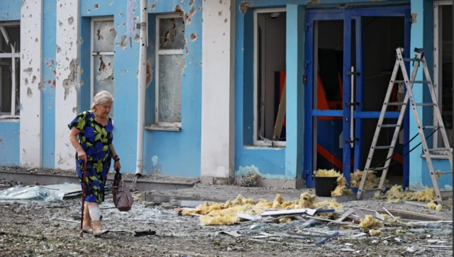 Umugore urimo kugenda anyura iruhande rw’inyubako ya banki yangirikiye mu gitero cya ‘drone’ Ukraine yagabye i Belgorod, mu Burusiya, ku itariki ya 9 Kanama (8) mu 2026