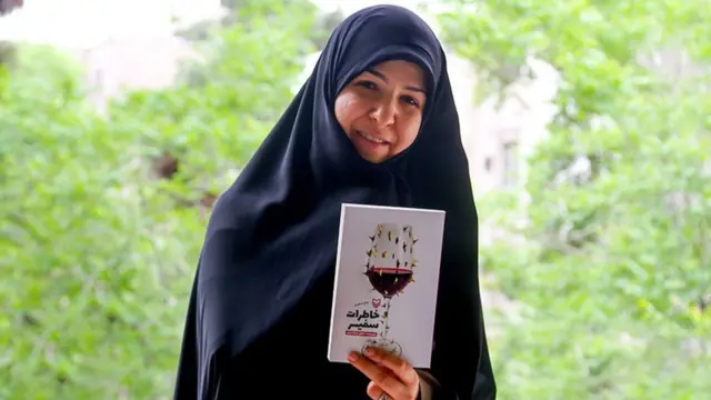 نیلوفر شادمهری با چادر سیاه و کتاب خاطرات سفیر در دست