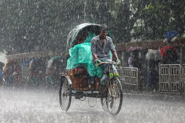 বৃষ্টির মধ্যে একটি রিকশা চলছে